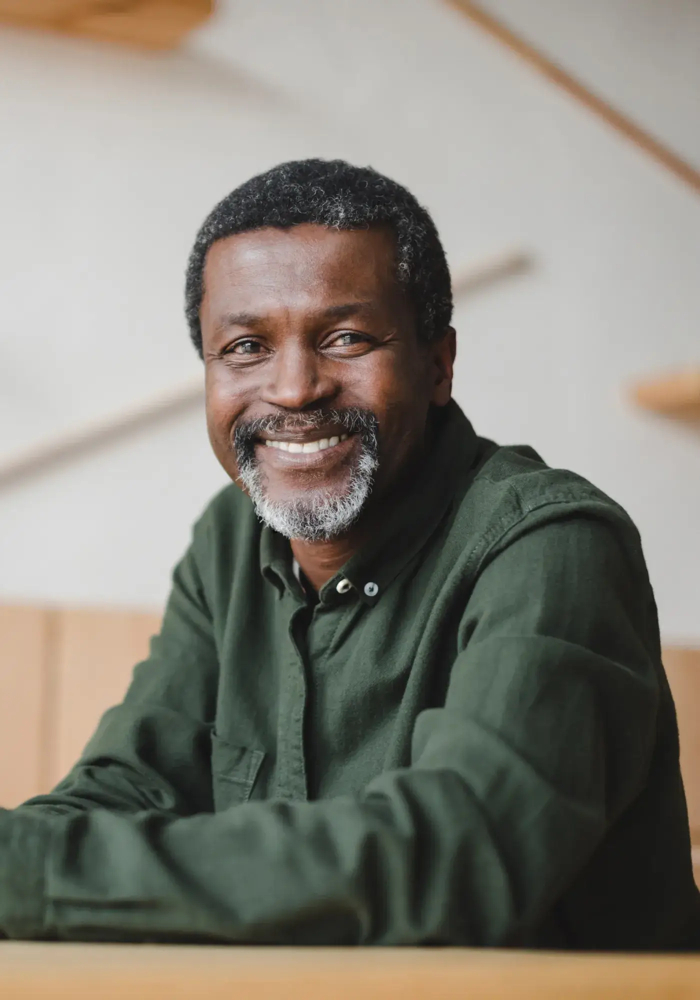 Smiling middle-aged man with short curly hair and gray beard wearing a dark green shirt.