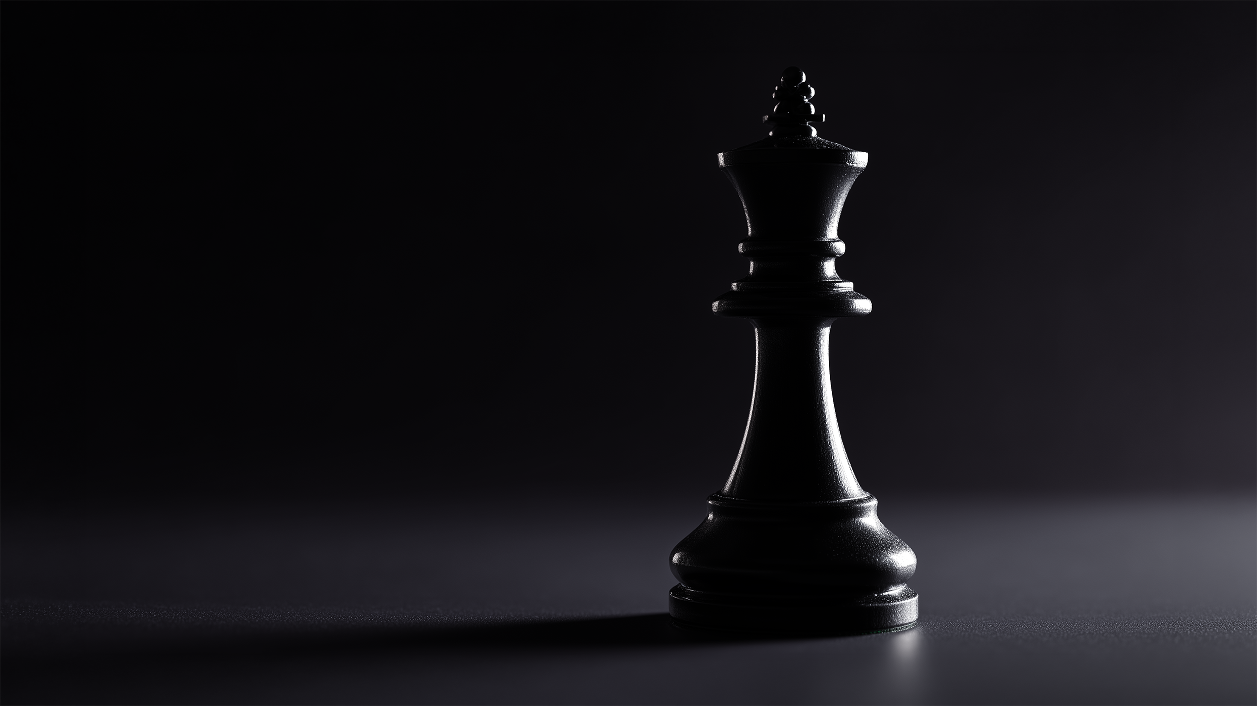 Close-up of a black chess king piece casting a shadow on a dark surface.