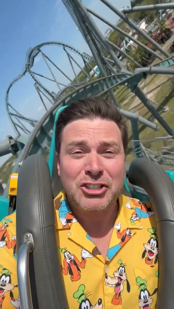 Frame 01, the hook: the man in the Goofy-print shirt reacting mid-ride, coaster track spiralling overhead