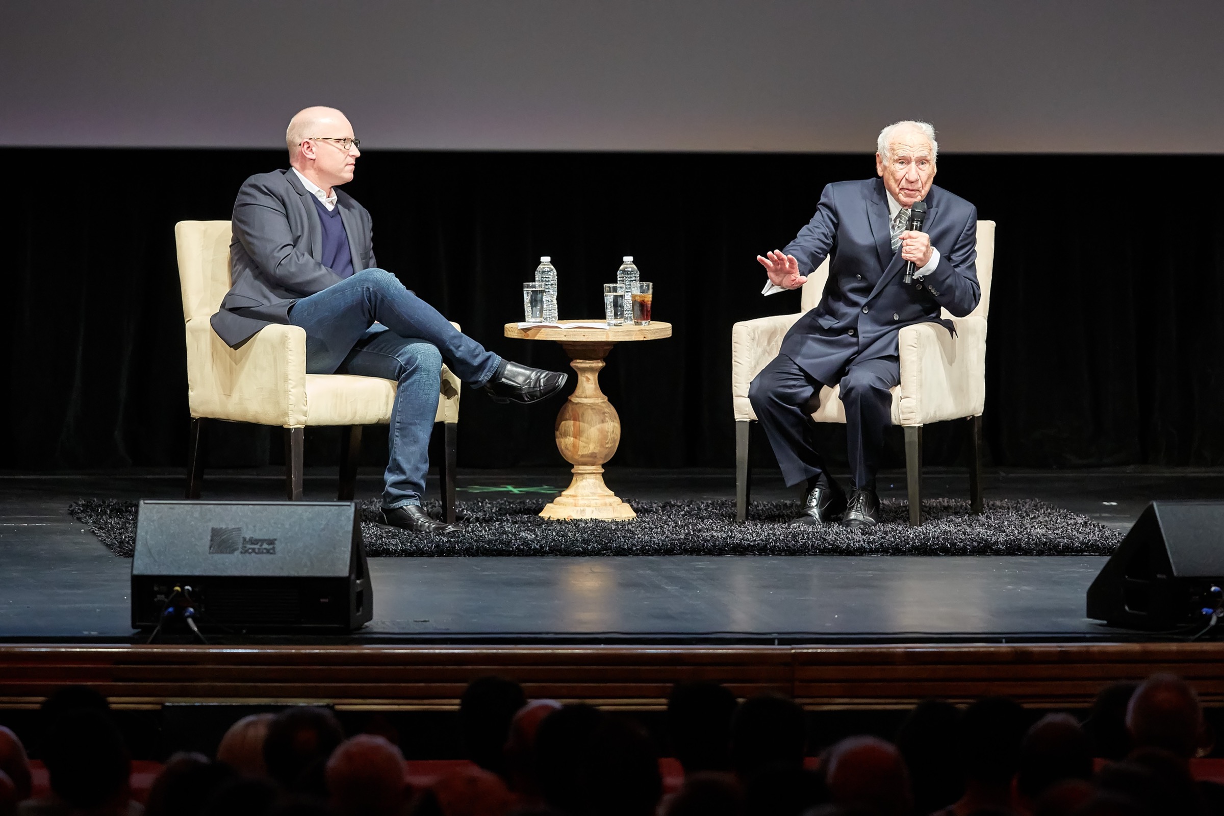 Mel Brooks on stage in Los Angeles, seated with a moderator in front of a full house