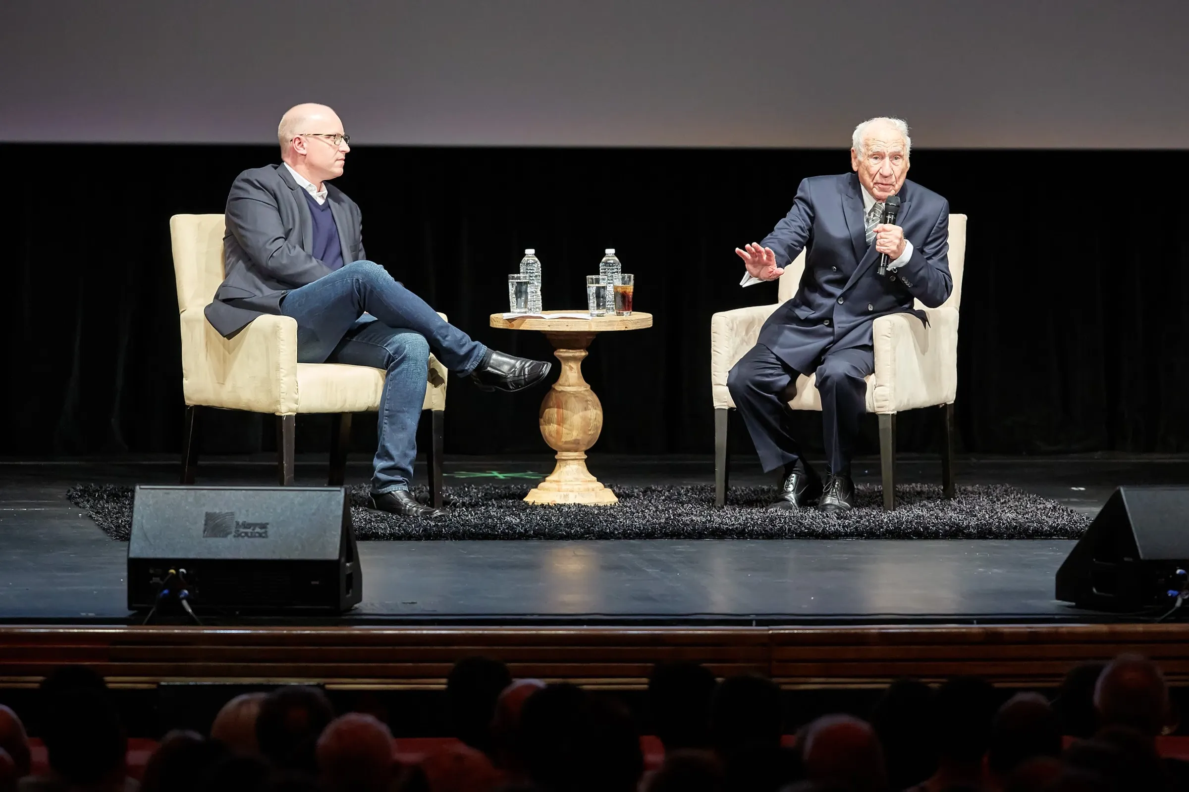 Mel Brooks on stage in Los Angeles, seated with a moderator in front of a full house