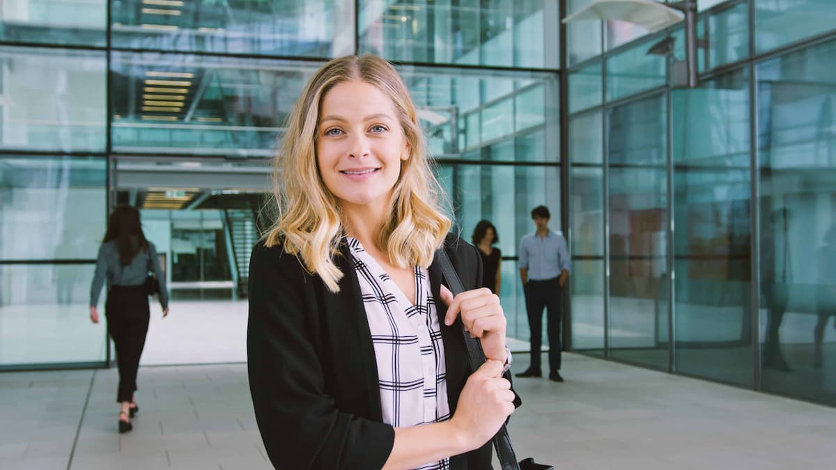 A woman standing outside an office building with people in the background