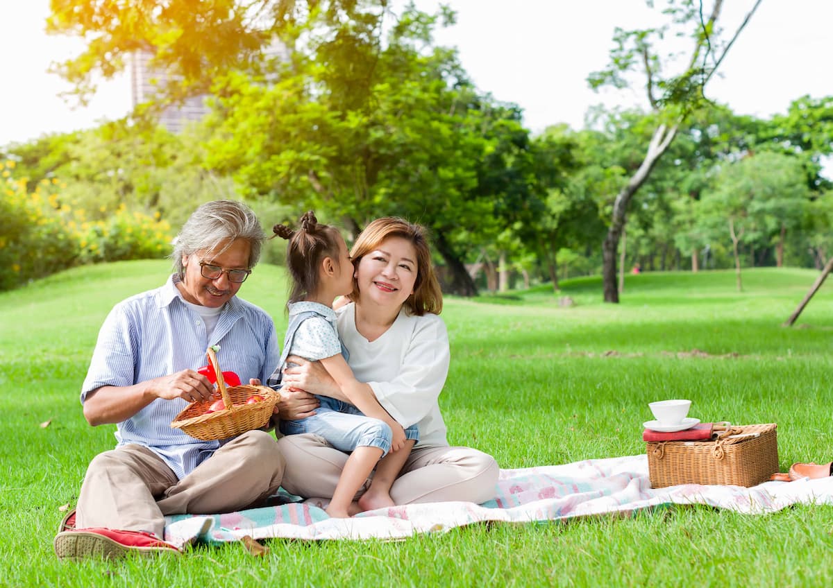 An older couple spending time with a child during a picnic in a park