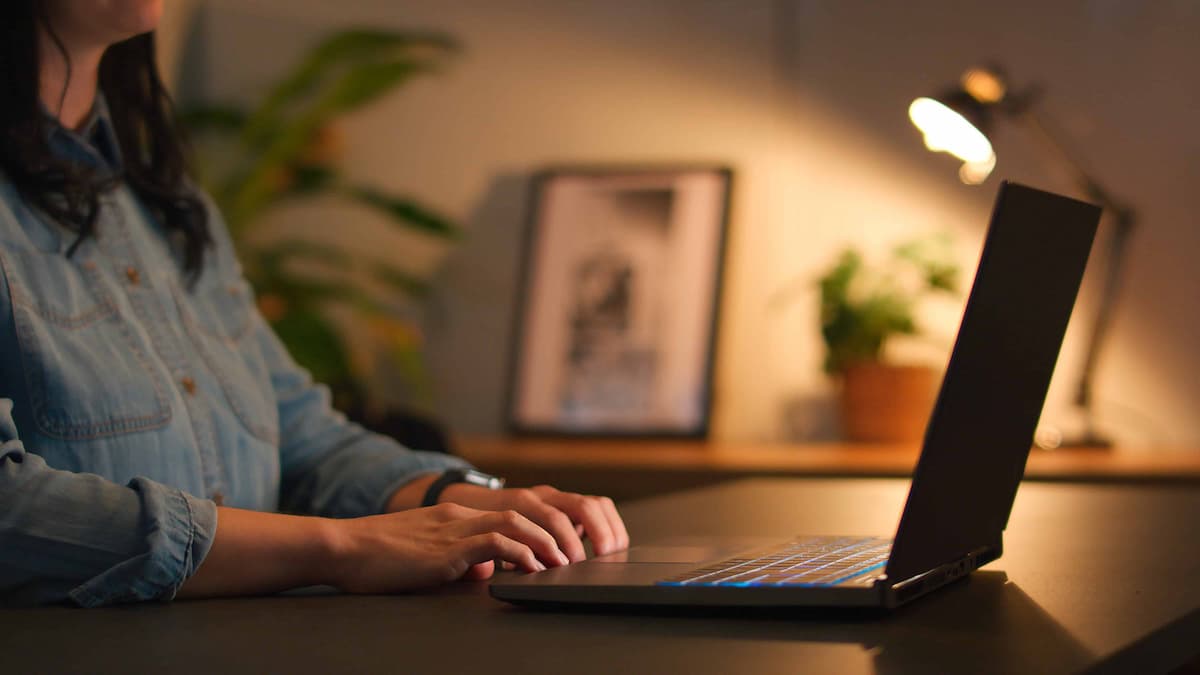 Hands typing on a laptop at a desk in a work environment