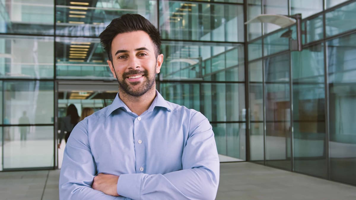 A man standing with his arms crossed inside a modern office building