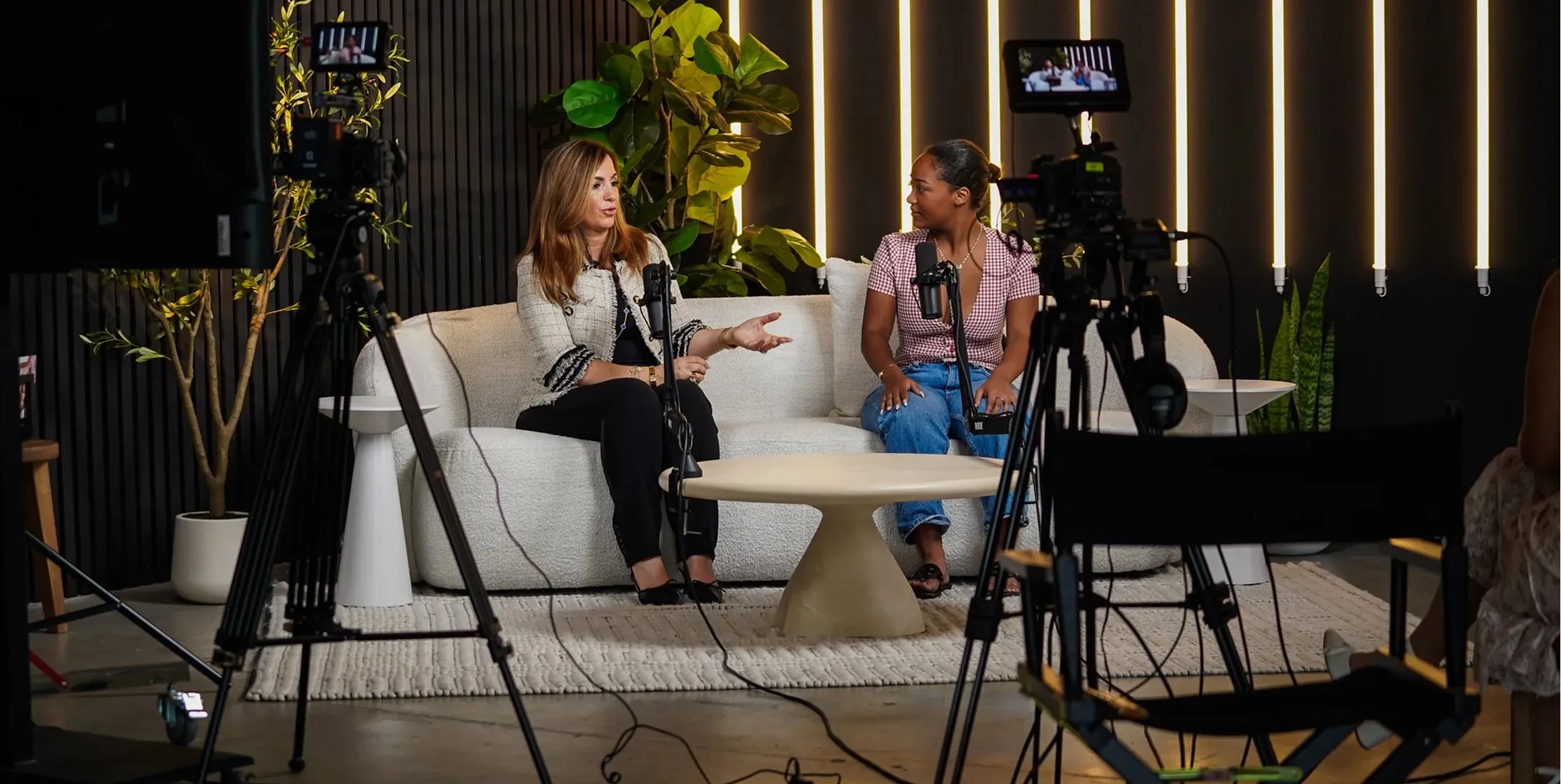 Two women sitting on a couch talking to each other.