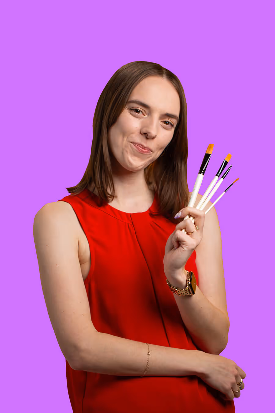 Woman in red sleeveless top holding four paintbrushes against a purple background.