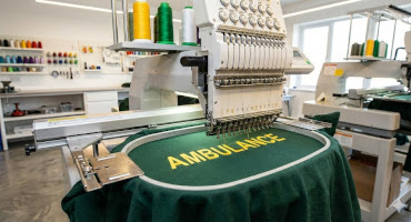 Embroidery machine part way through an ambulance polo t-shirt