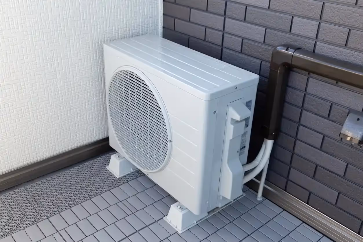 A single mini-split air conditioning unit placed on the ground next to a building.