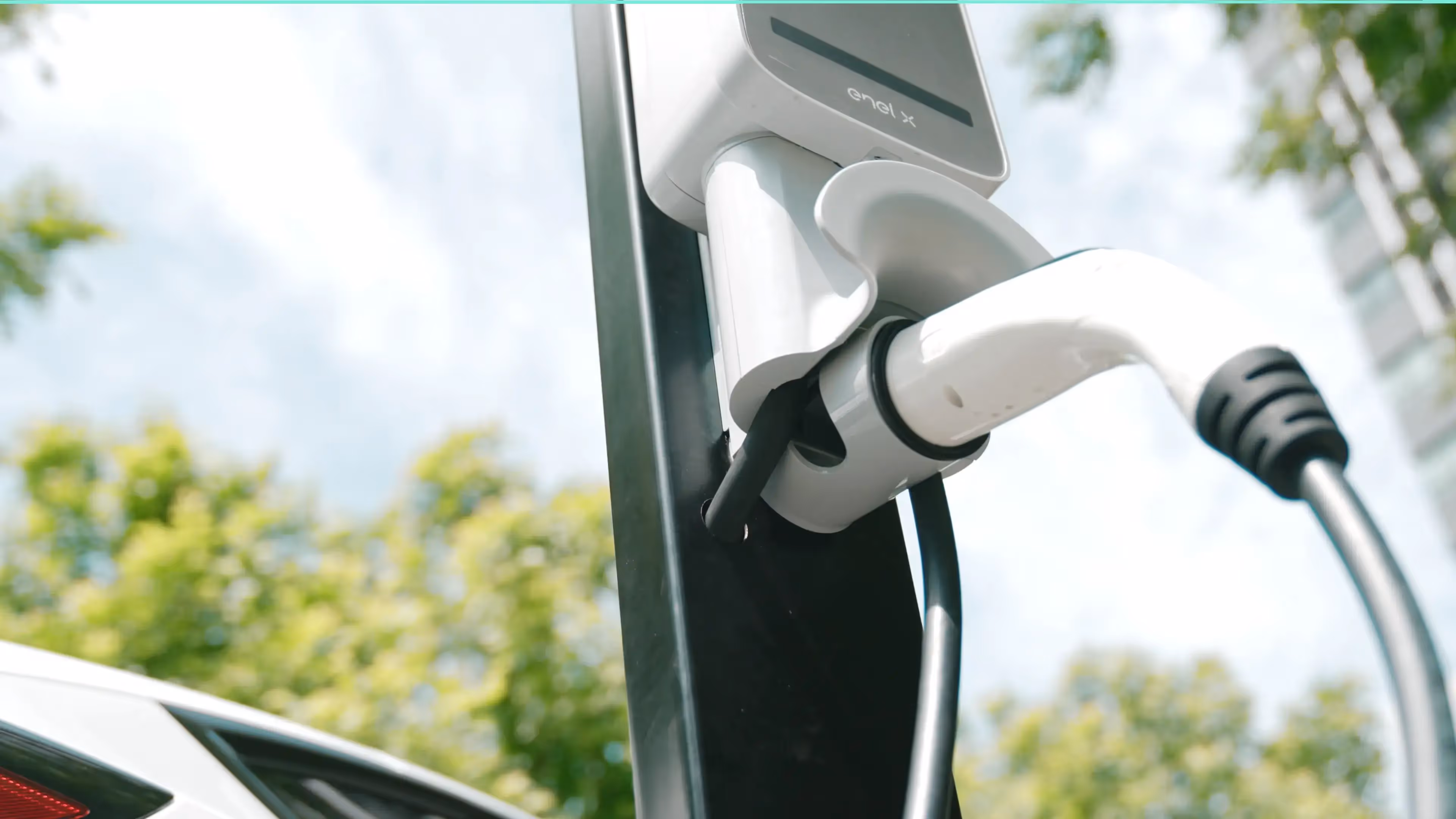 Close-up of a white EV charging cable handle plugged into an electric car.