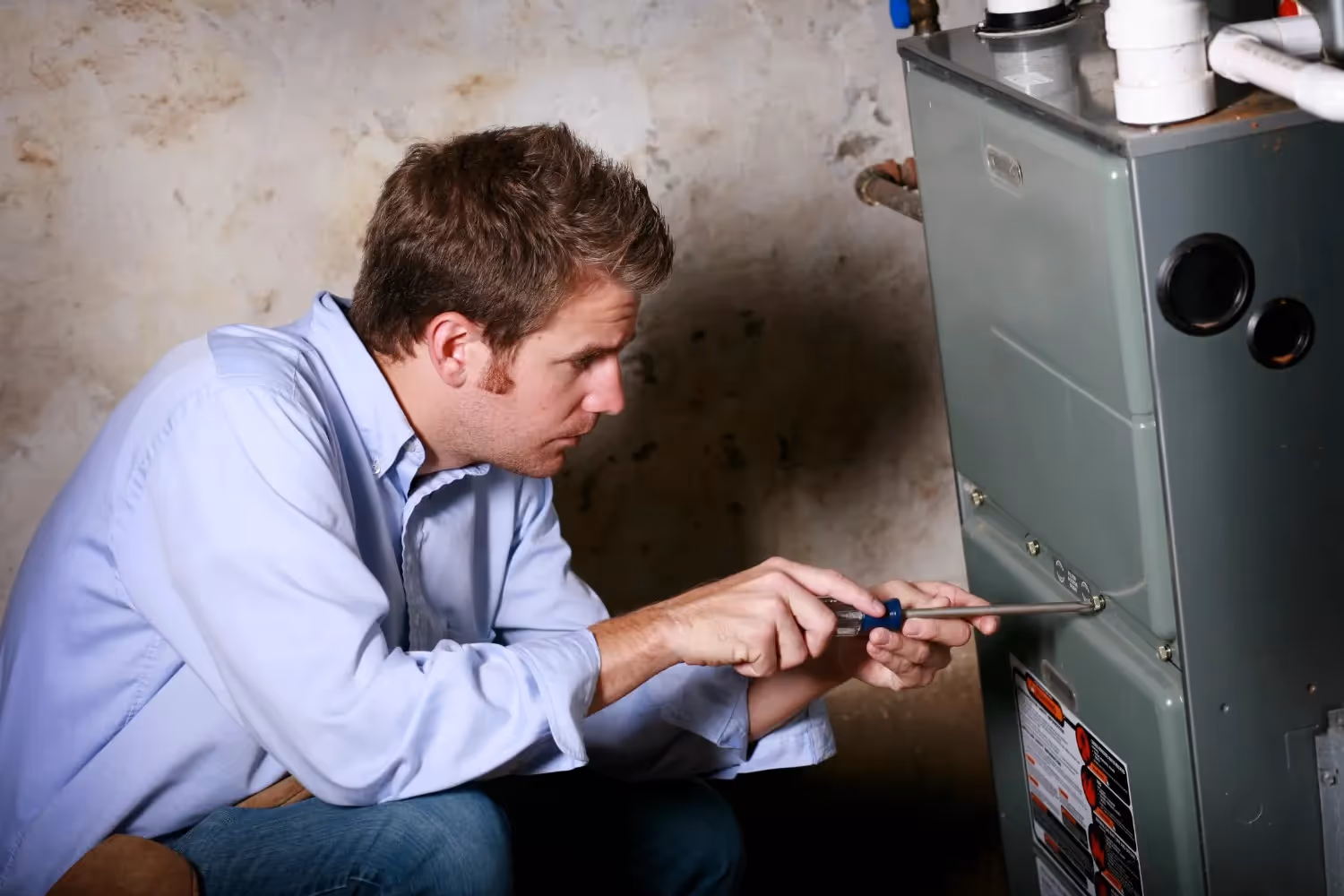 Technician or plumber kneeling to install or inspect a white panel-style hydronic radiator