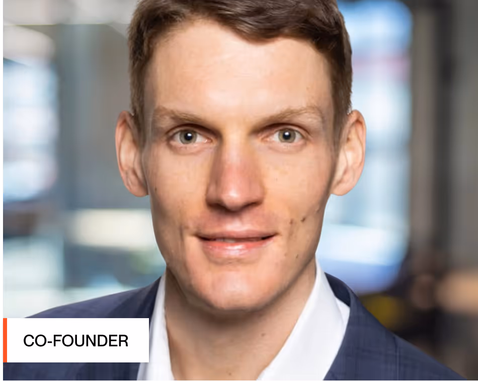 Headshot of Christian Ruf, co-founder of Strongpoint Talent with short brown hair wearing a dark suit jacket and white shirt in a blurred indoor office background.
