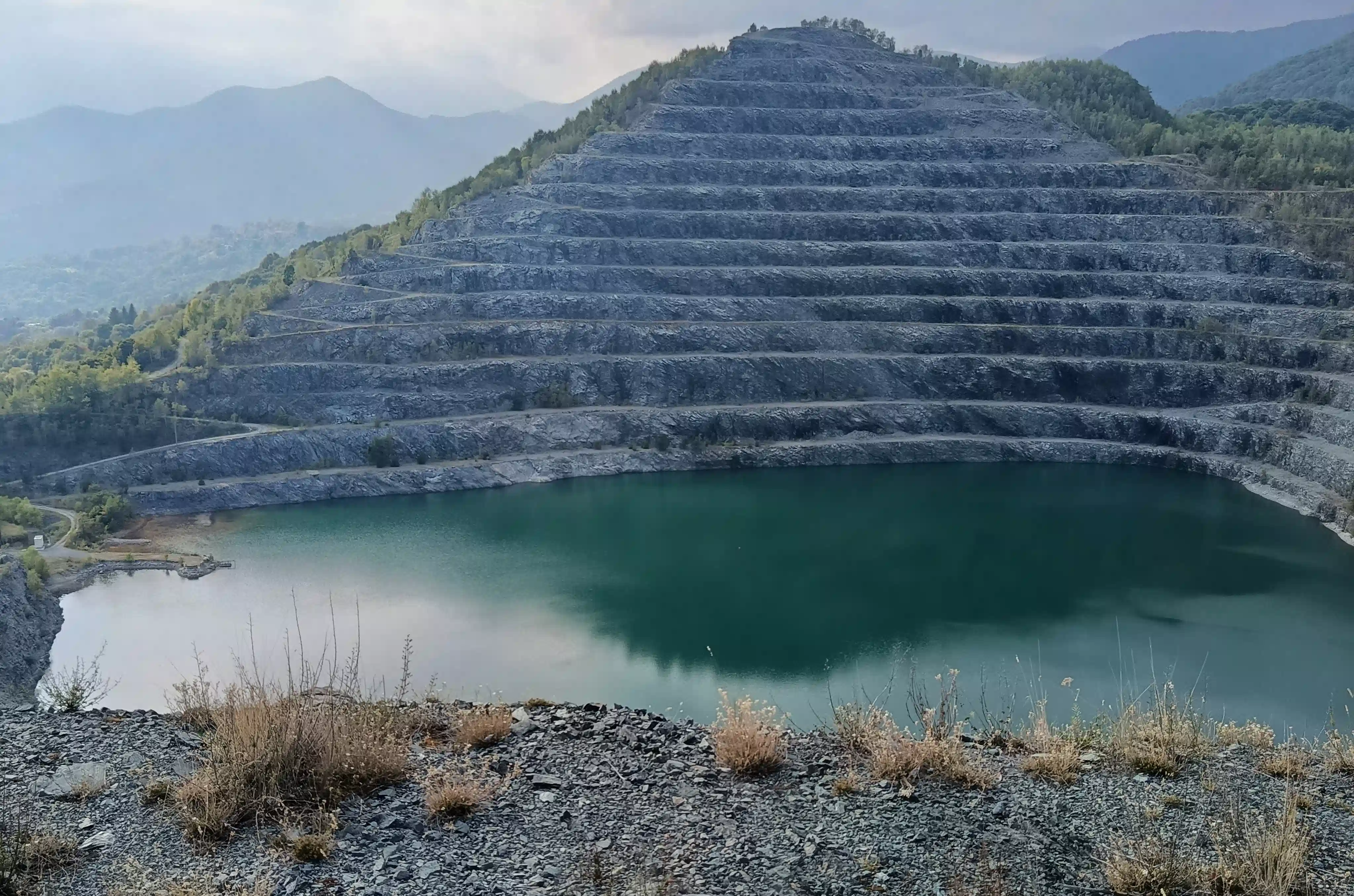 Bacino minerario dell’ex miniera di Balangero con lago verde smeraldo e versanti terrazzati.