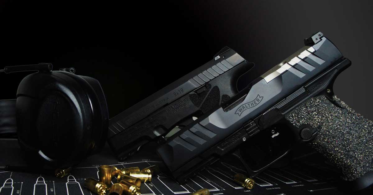 Person in black clothing safely holding a white handgun across their waist with both hands.