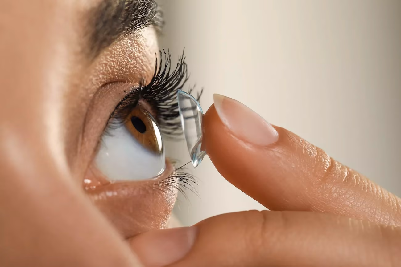 A lady inserting one contact lens to her eye.