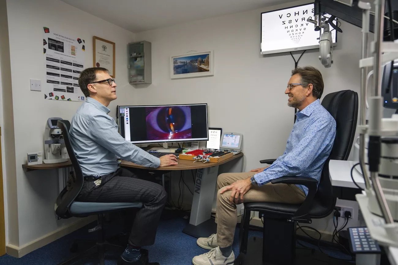 Optician and patient reviewing an eye scan image together during a consultation.