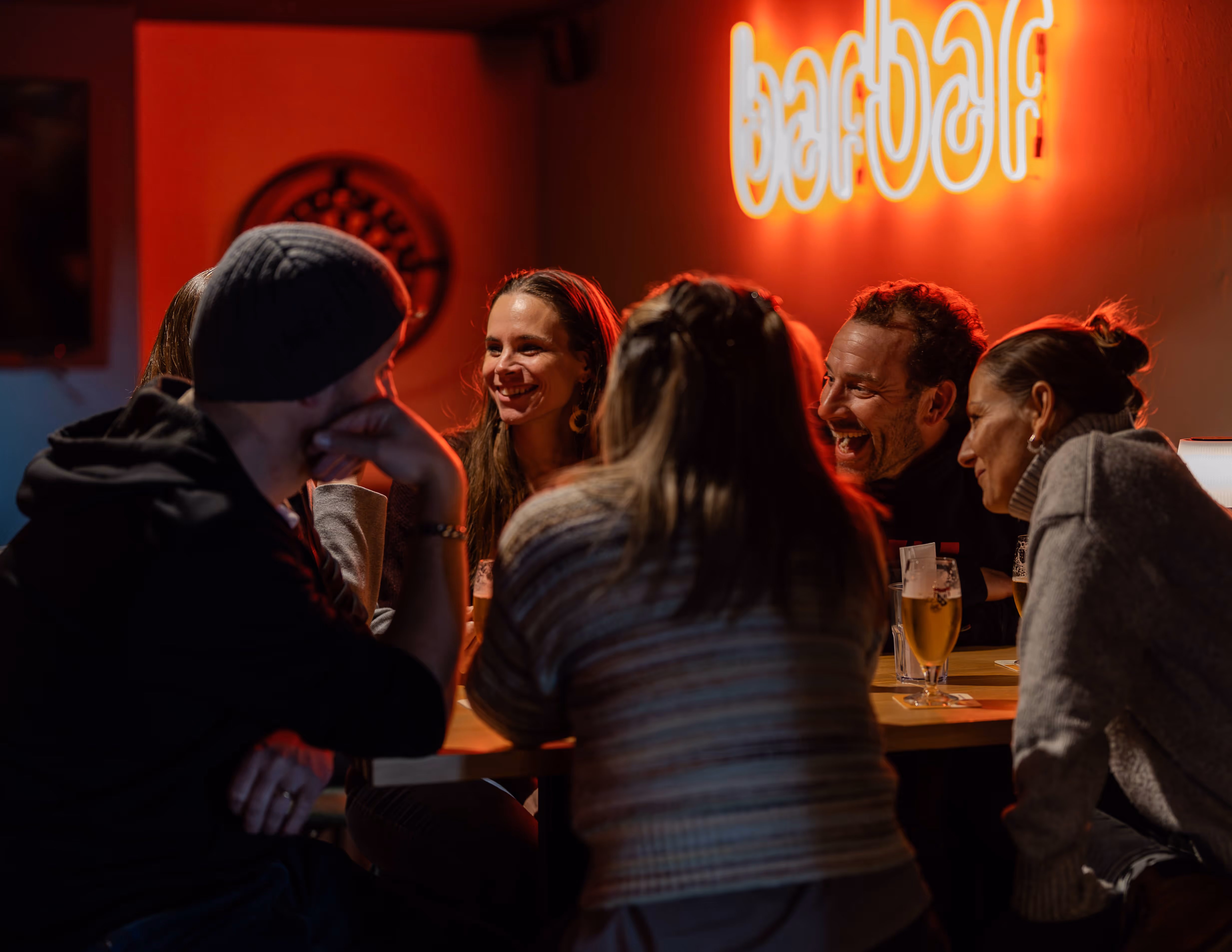 Fünf Personen lachen und unterhalten sich an einem Tisch in der Barbar.