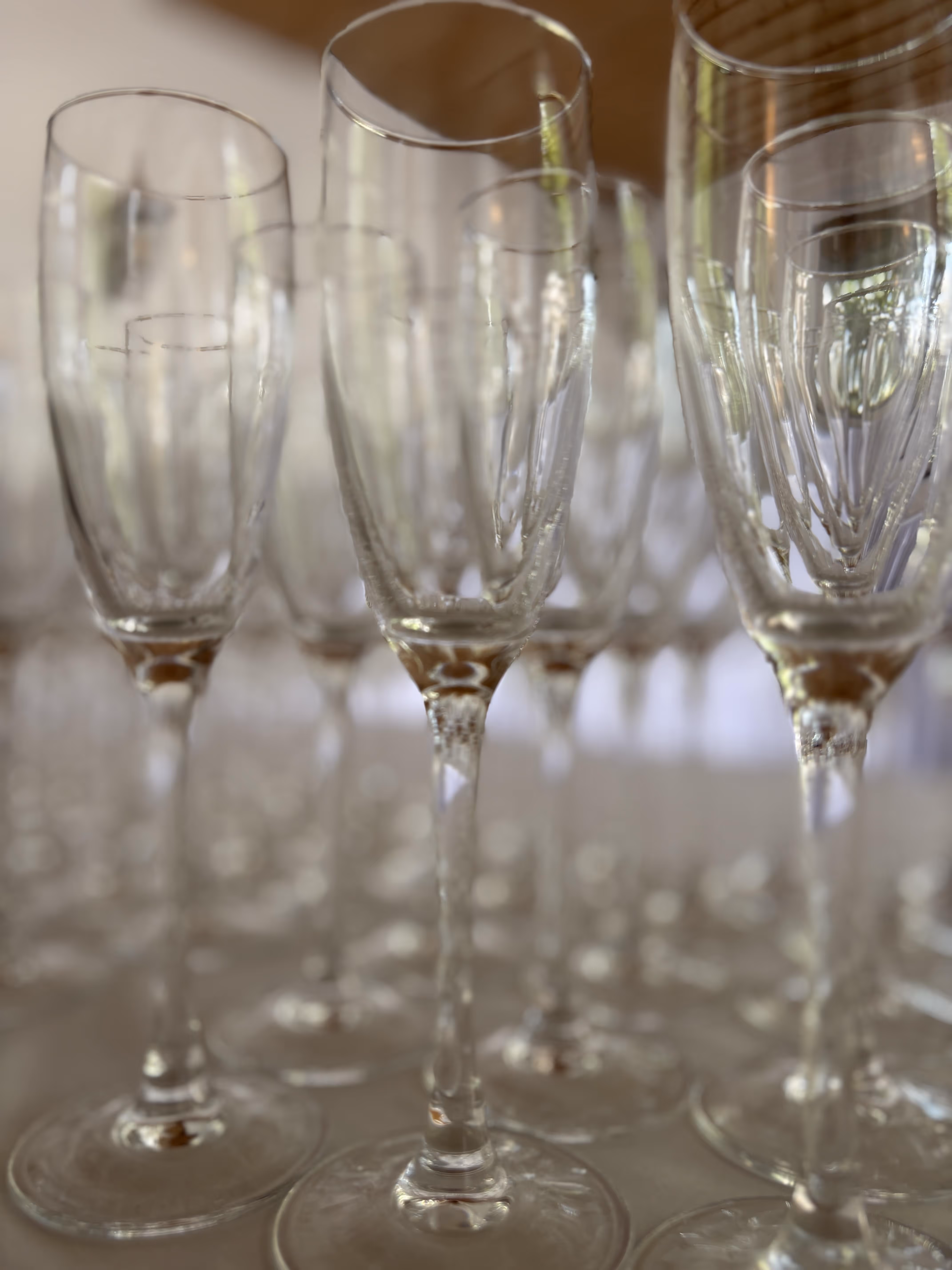 Nahaufnahme von mehreren leeren, transparenten Sektgläsern auf einem Tisch.