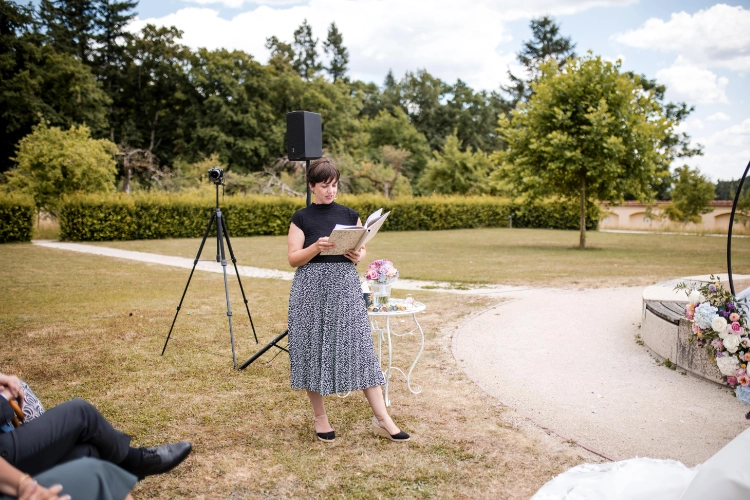 Anna Fasciani - freie Traurednerin -  steht draußen in gepflegtem Garten und liest aus einem Buch bei freier Trauung.
