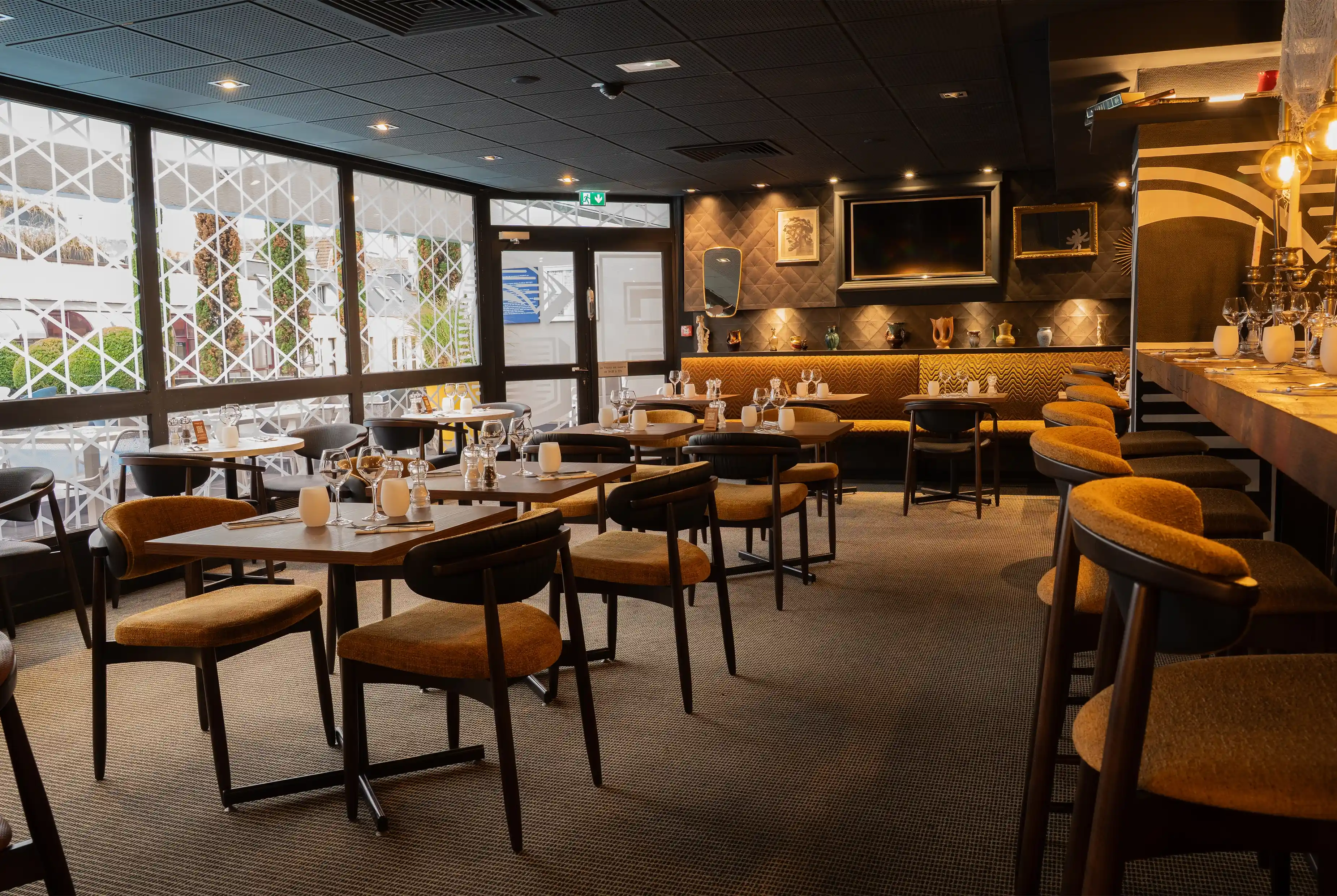 Stijlvol restaurantinterieur met gestoffeerde stoelen, gedekte tafels en groot wandscherm, zachte verlichting.