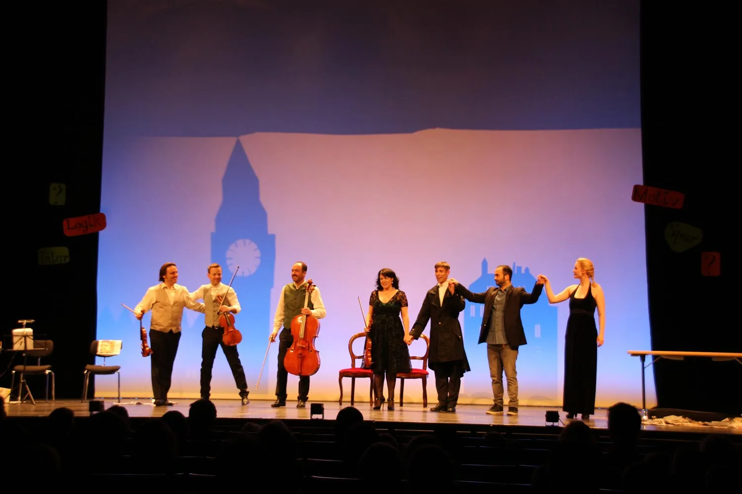 Zwei Sänger auf einer Bühne bei einem Konzert mit Mikrofonen und bunten Bühnenlichtern.