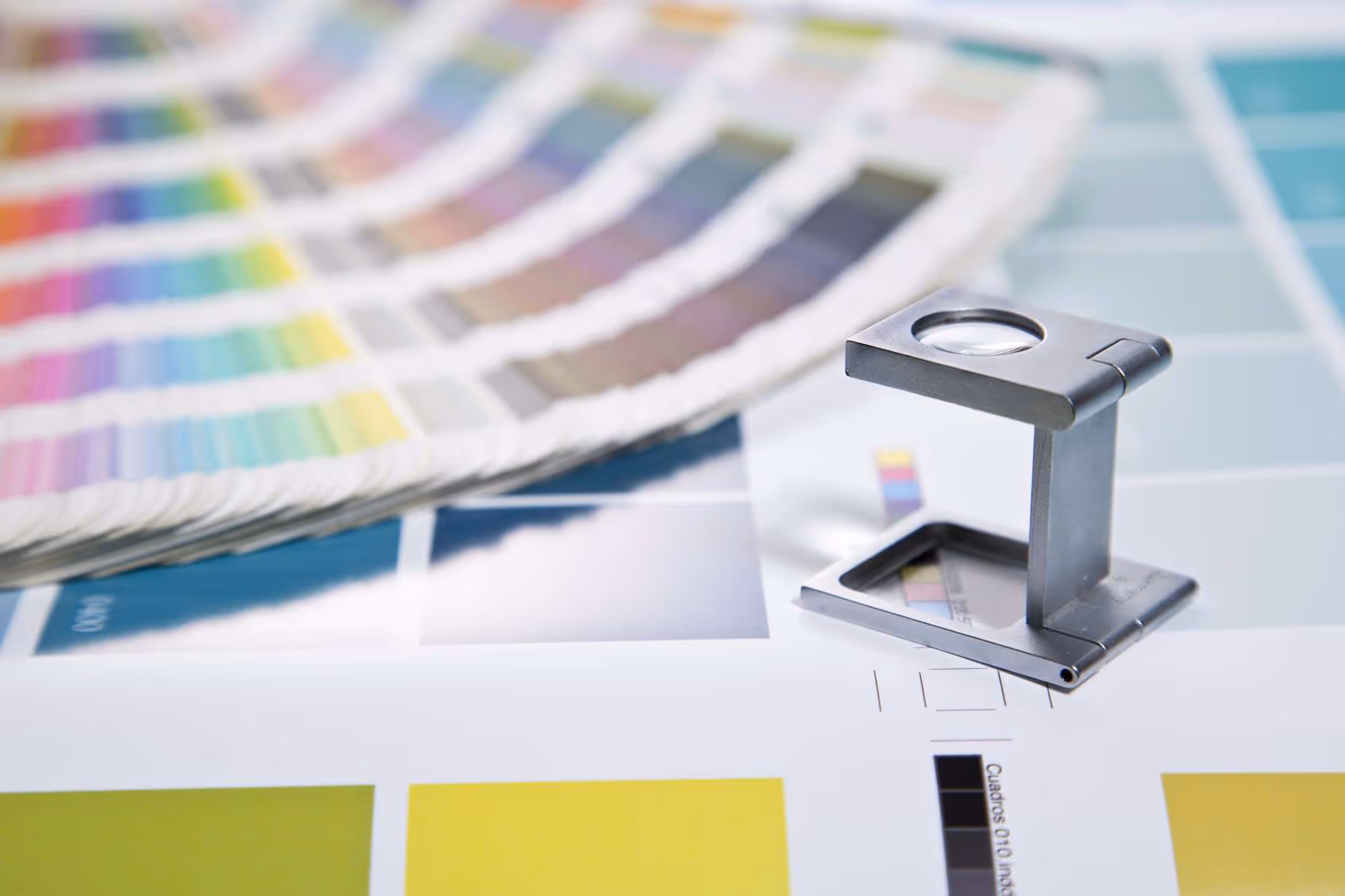 Lupa de aumento sobre várias amostras de cores em papel para design gráfico.