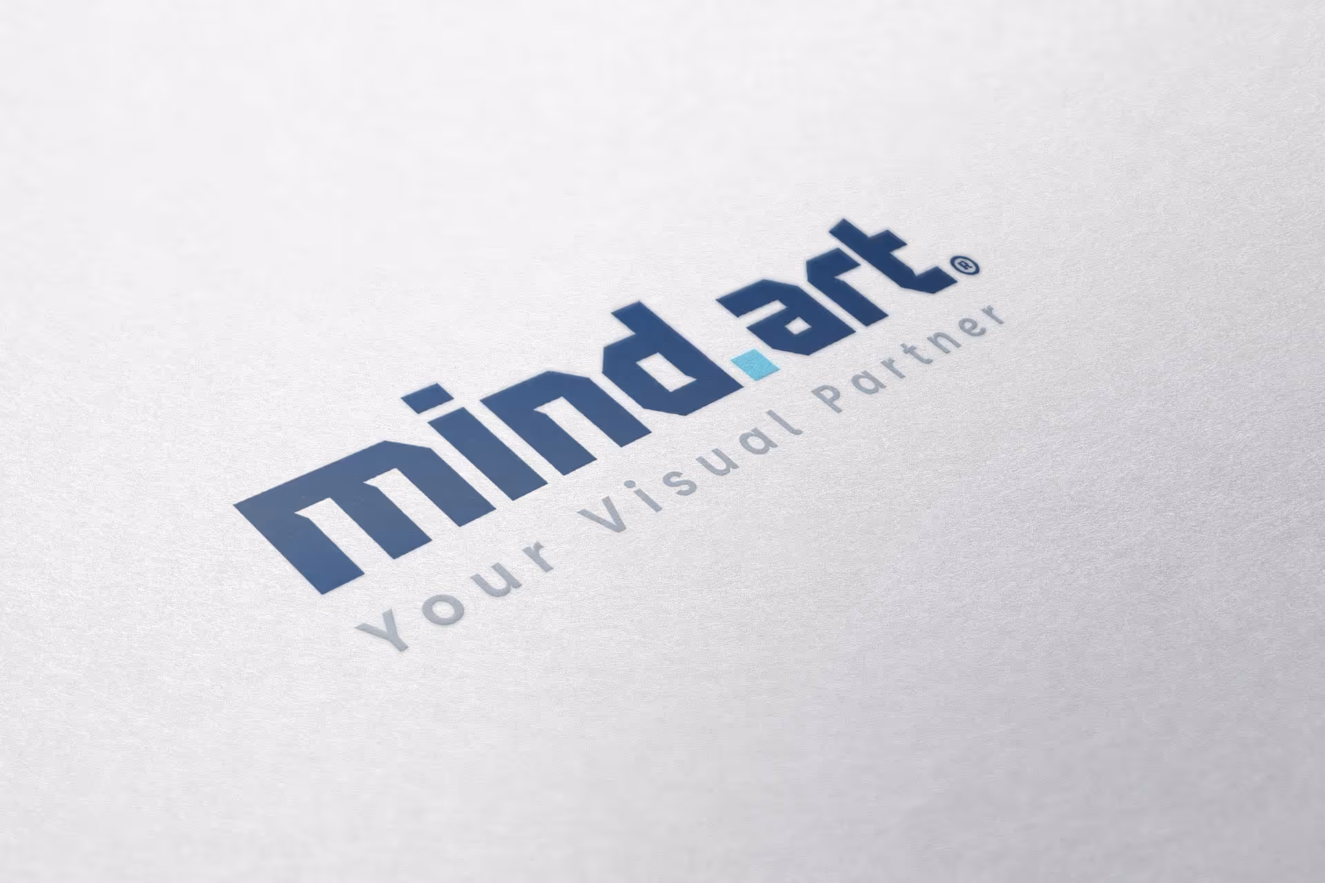 Logótipo Mind.Art com o slogan 'Your Visual Partner' impresso em papel branco.