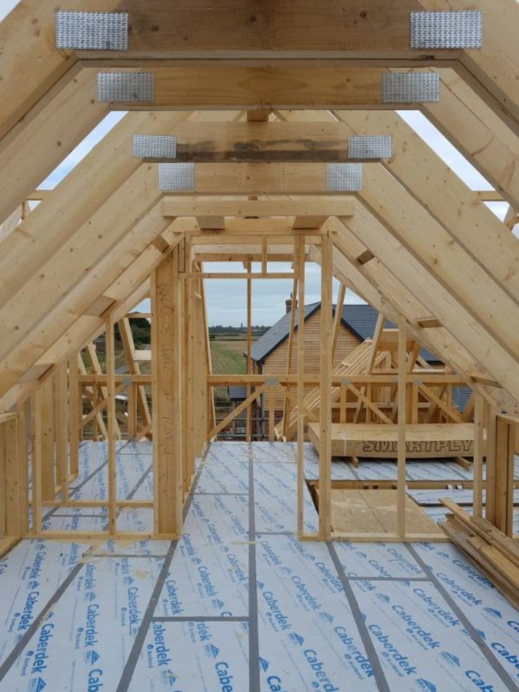 Interior view of a wooden house frame under construction with roof trusses.
