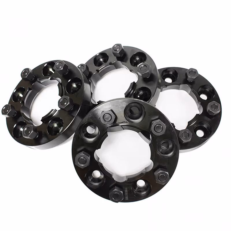 Four black metal wheel spacers with bolts arranged on a white background.