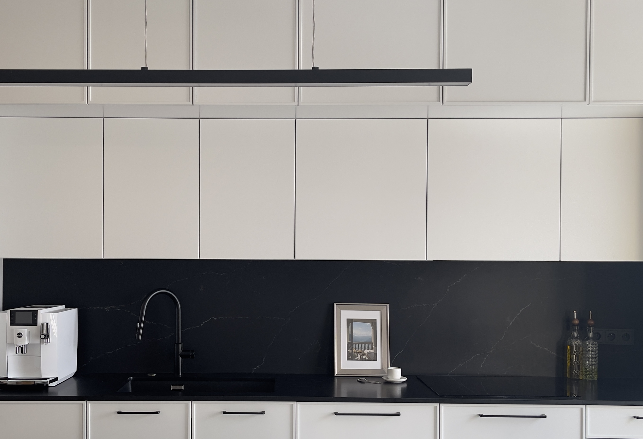 Zdjęcie poglądowe całości zabudowy białej kuchni z frezowanymi frontami.