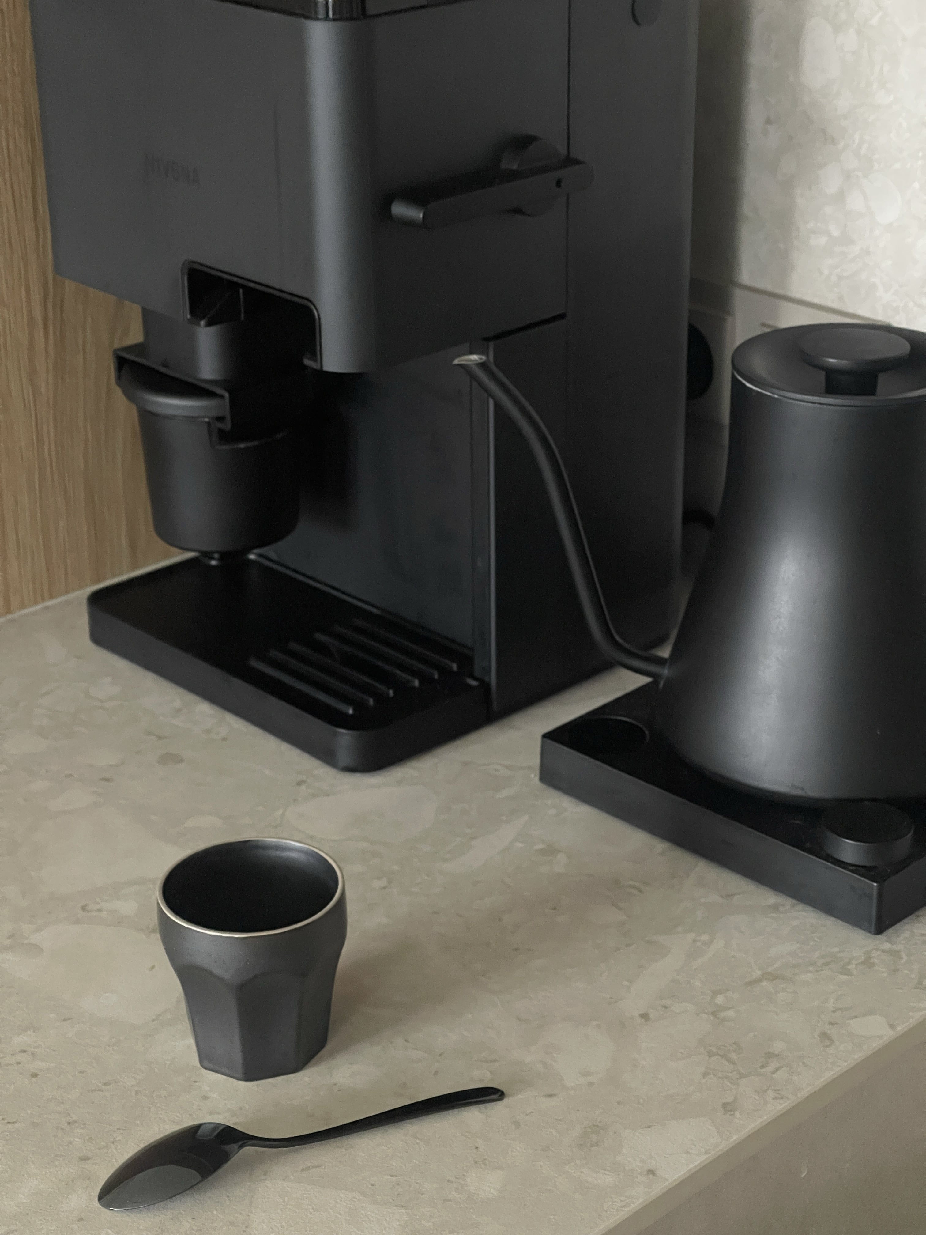 Kącik kawowy w kuchni z blatem ze spieku Dekton Ava, pokazujący ekspres do kawy Nivona Cube oraz czajnik Fellow Stagg w kolorze czarnym.