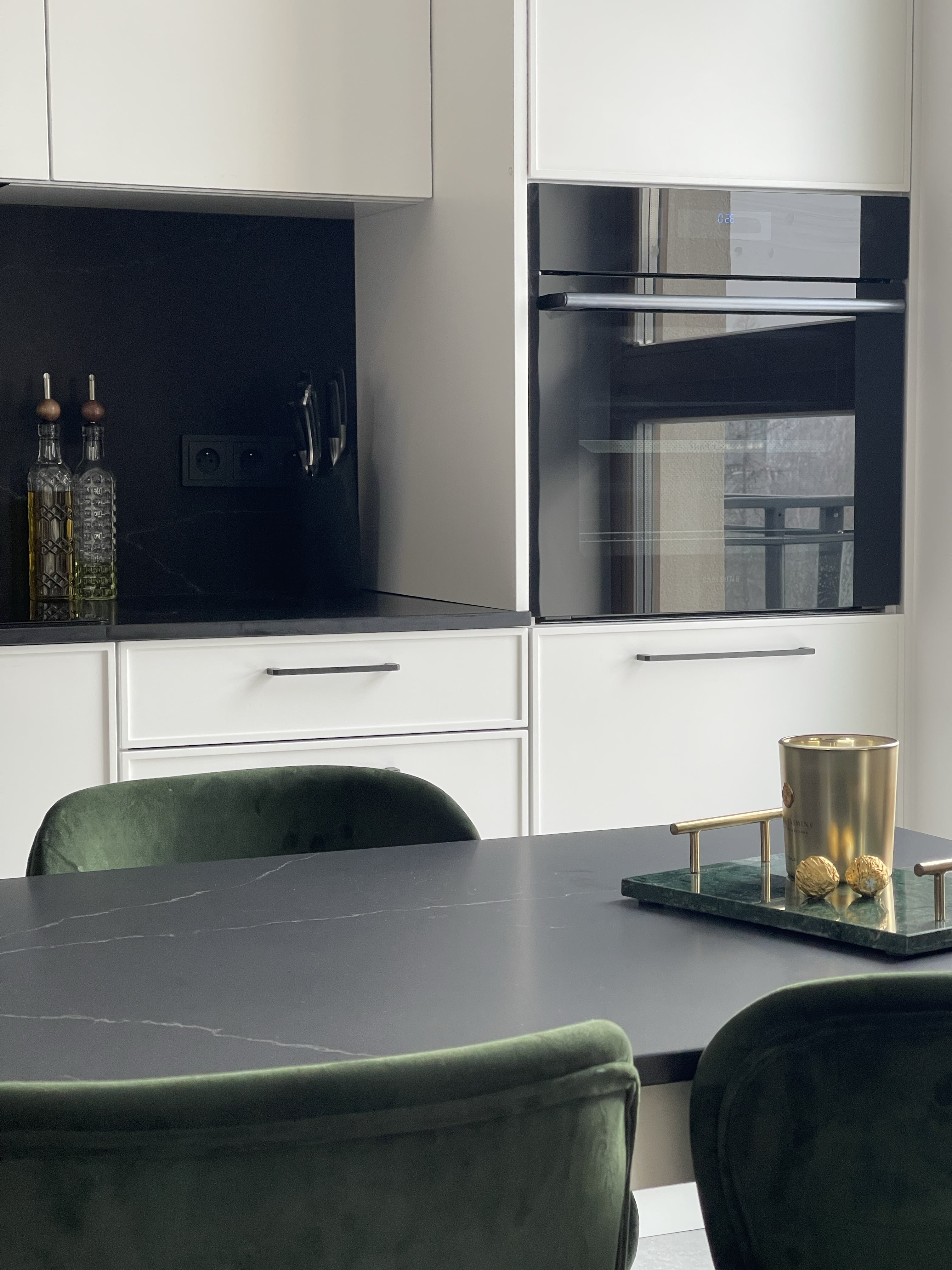 Zdjęcie z realizacji kuchni premium pokazujące stół kuchenny oraz fragment blatu i piekarnik w słupku.