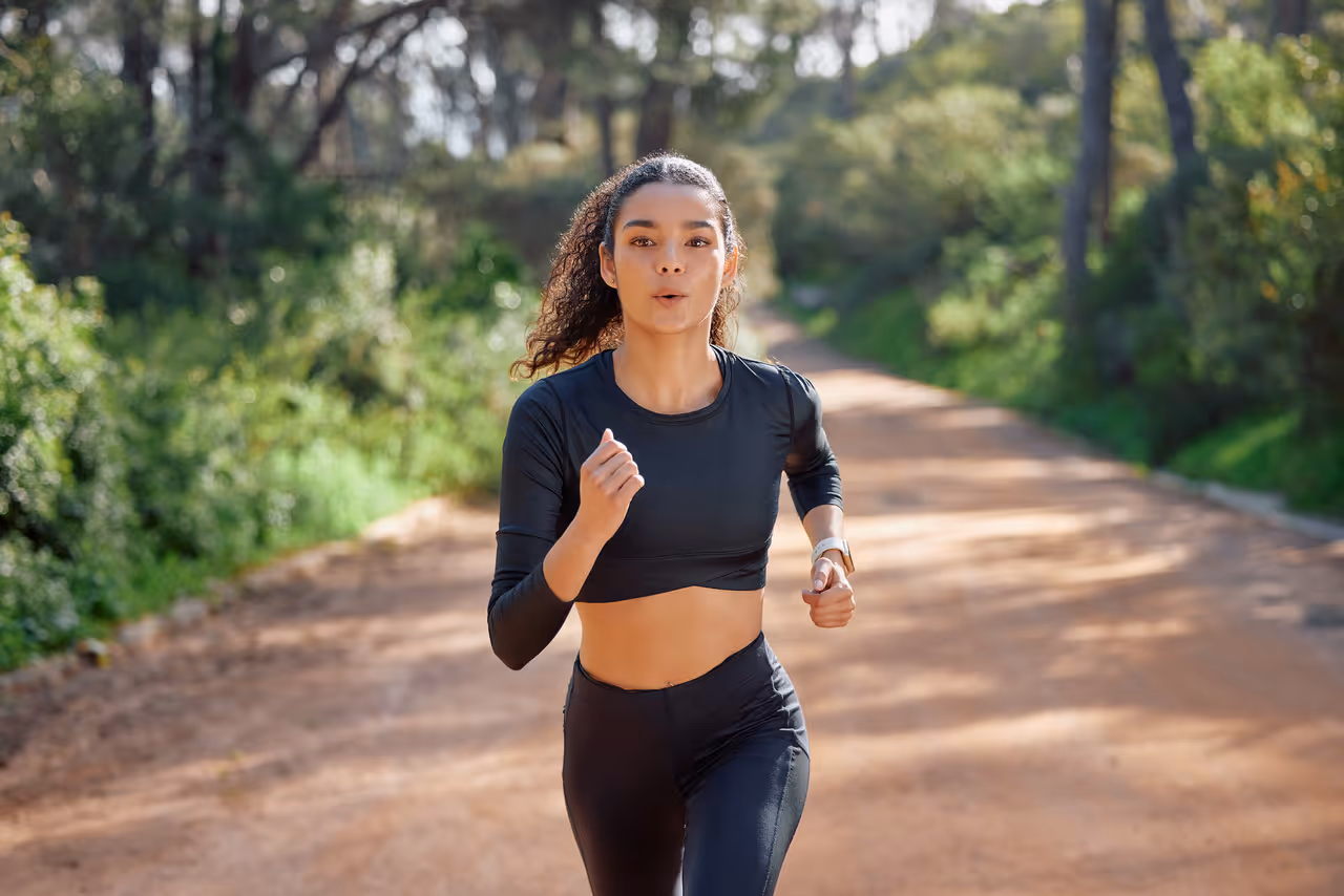 Woman running on a trail in Surrey at the Queens community area, enjoying outdoor exercise surrounded by greenery.