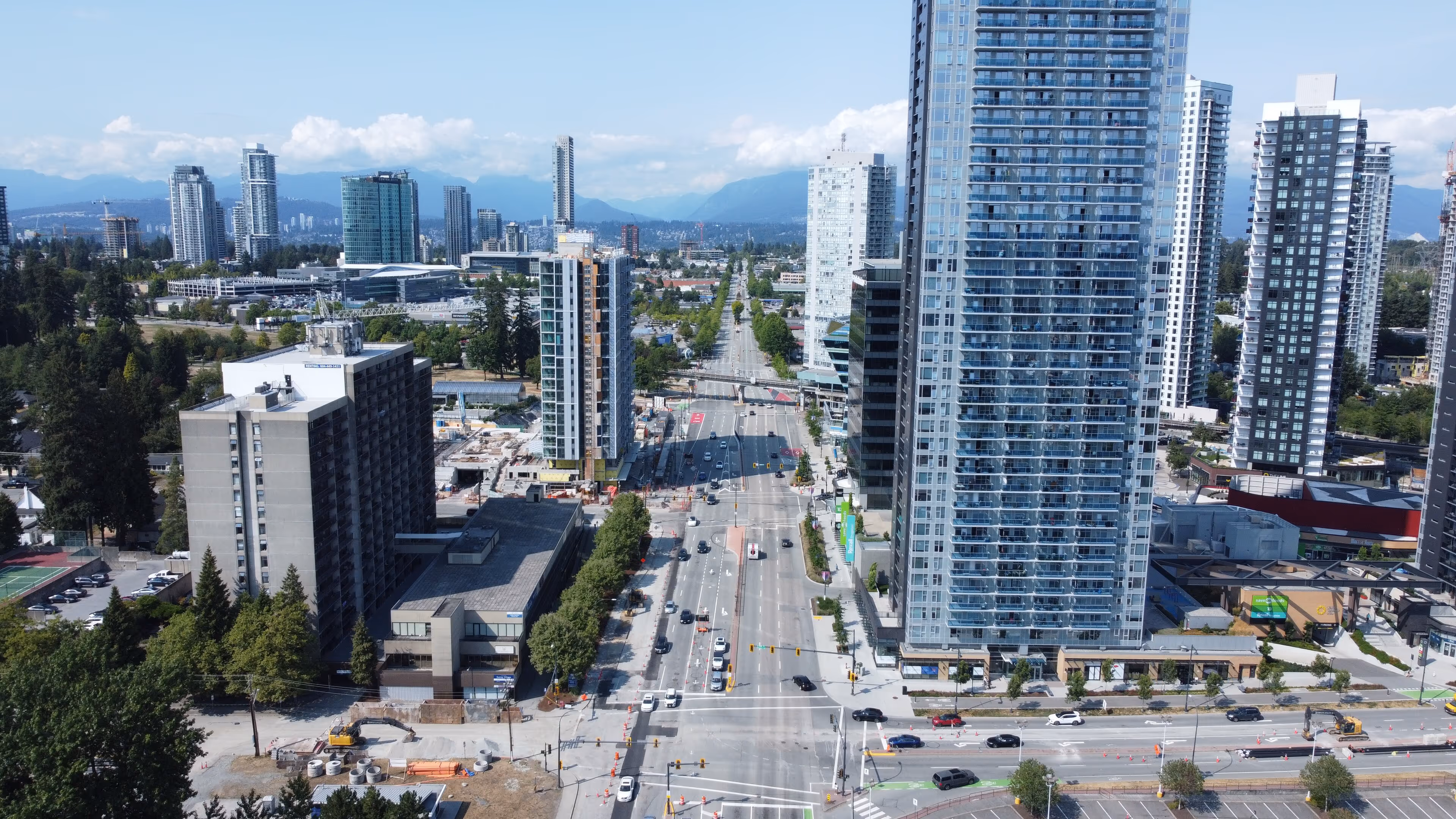 Aerial view of a wide urban boulevard lined with tall modern residential and office buildings under a blue sky.