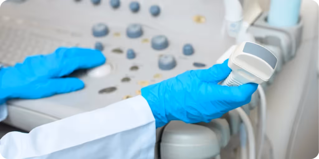 Close-up of a laboratory professional’s gloved hands operating an ultrasound probe connected to a medical imaging console, with control knobs and interface visible. The scene represents clinical diagnostics, medical device use, and regulated healthcare technology environments relevant to product compliance, device registration, and market access in China and the Asia-Pacific regulatory landscape.