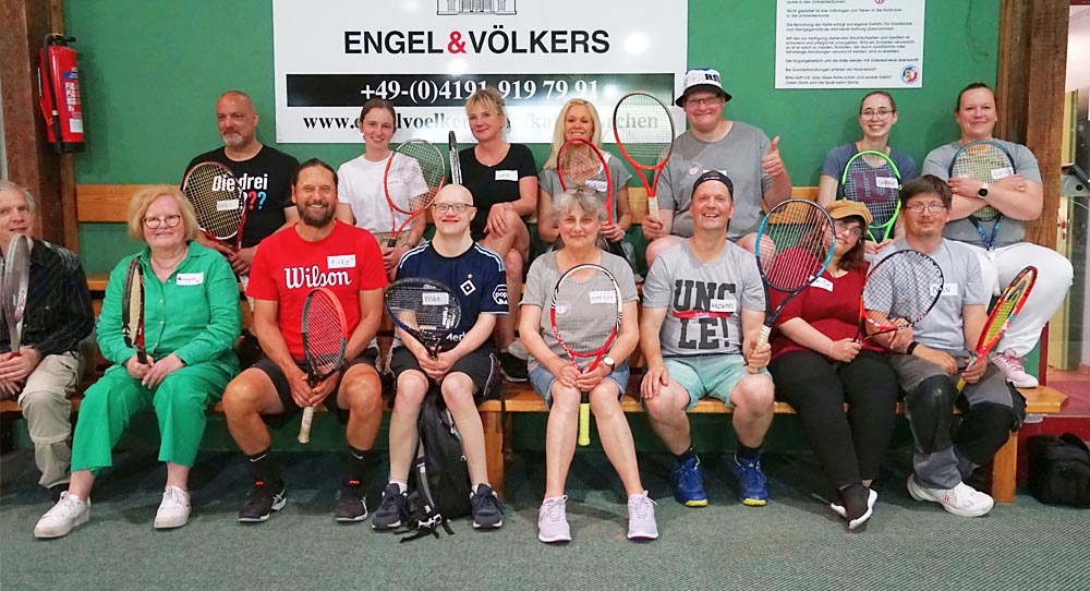 Viele Tennisspieler sitzen in Sportkleidung auf einer Bank beziehungsweise stehen dahinter.
