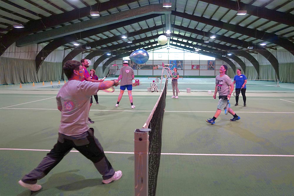 Mehrere Menschen spielen in einer Halle Tennis