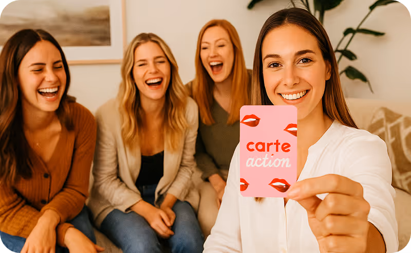 Quatre femmes souriantes assises sur un canapé, une tenant une carte rose marquée « carte action » avec des illustrations de lèvres rouges.