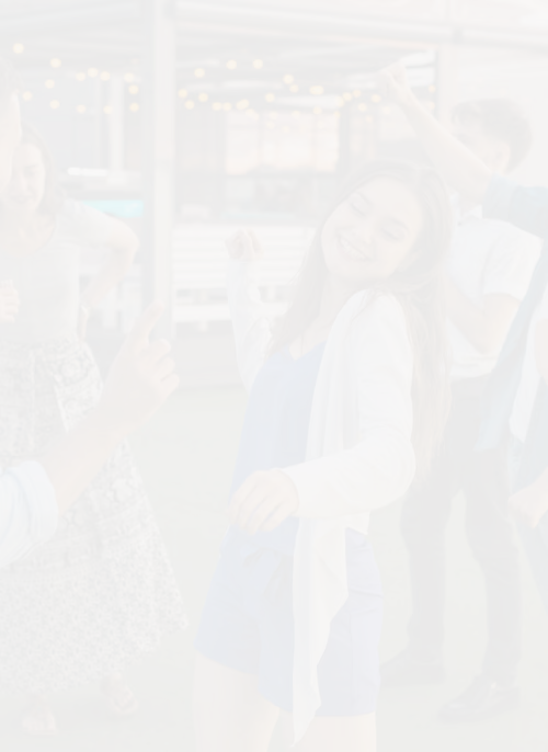 Un groupe de jeunes dansant et s'amusant en plein air lors d'une soirée avec guirlandes lumineuses en arrière-plan.