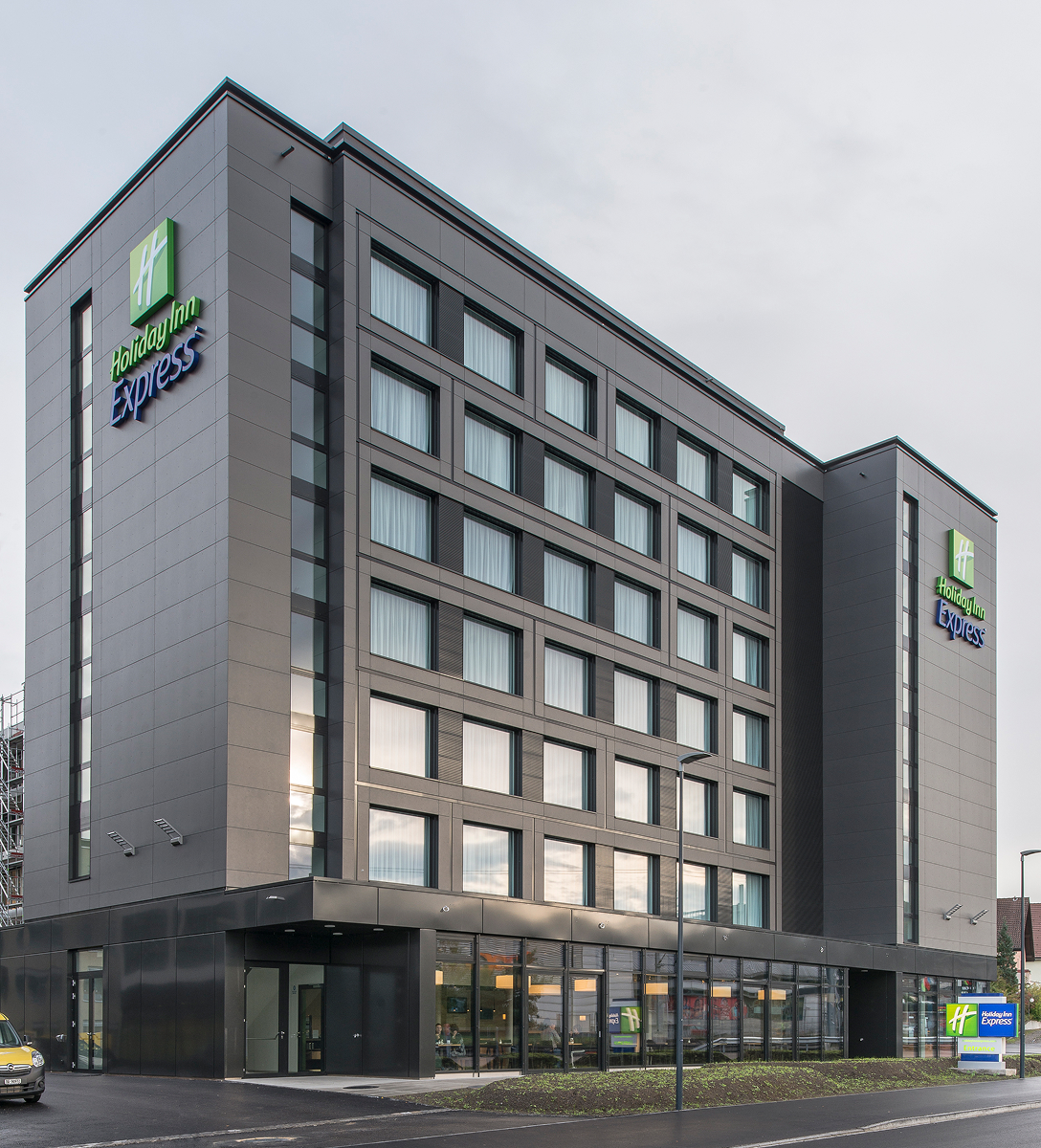 Modernes Holiday Inn Express Hotel in Affoltern am Albis mit vielen Fenstern und Eingangsbereich an einem bewölkten Tag.