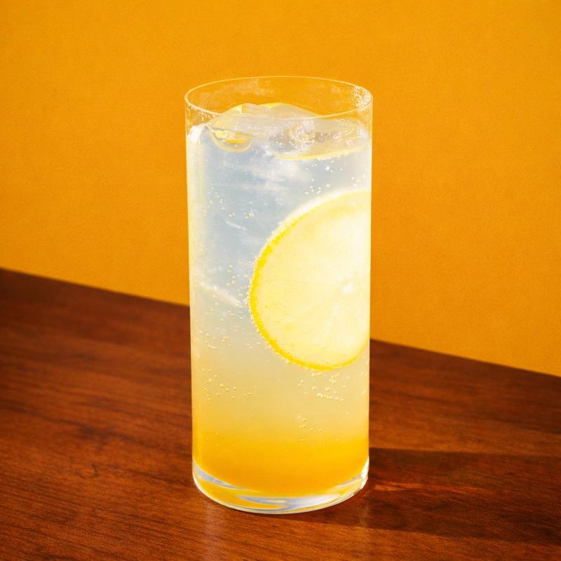 Cocktail made with gin, hot toddy mix and sparkling water on a blue background.