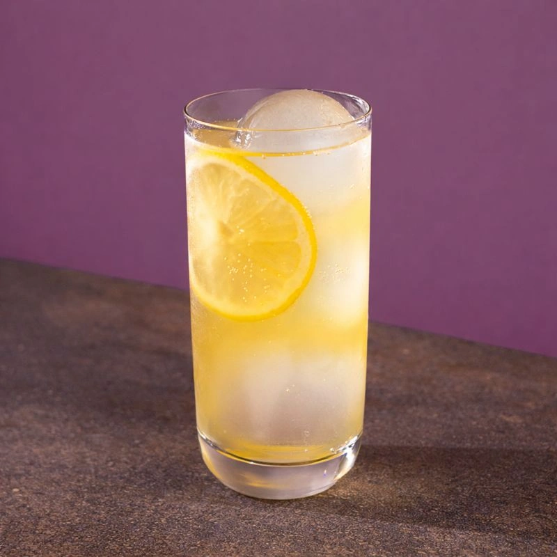 Cocktail à base d'amaretto, de sirop de pêche, de jus de canneberge et de limonade sur fond mauve.
