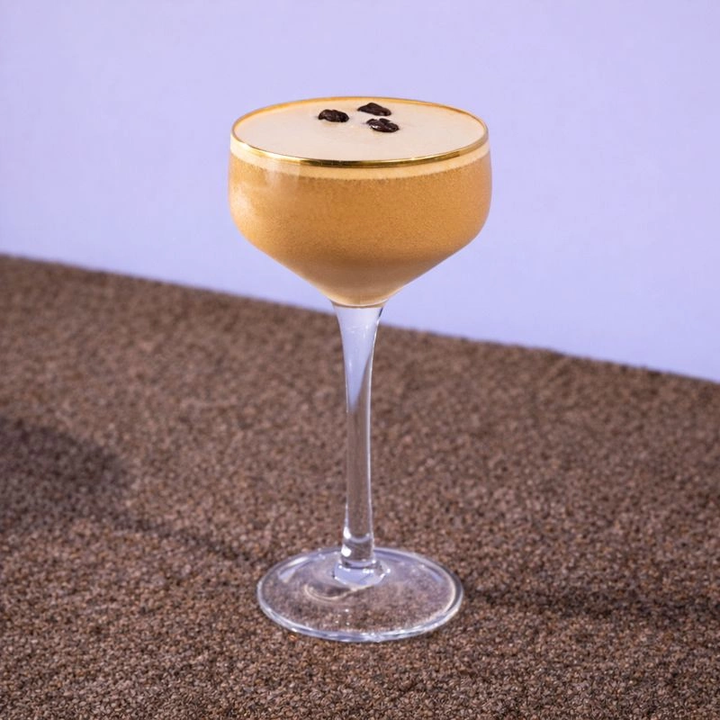 Cocktail made with vodka, alcoholic cream and espresso martini mix on a lilac background.