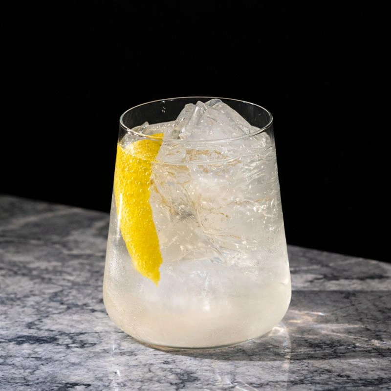 Cocktail à base de whisky, de sirop de pêche et d'eau pétillante sur fond jaune.