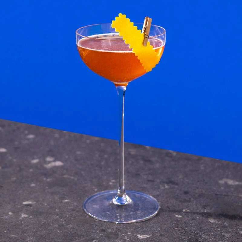 Cocktail made with bourbon, Italian aperitif, amaro and fresh lemon juice on a royal blue background.