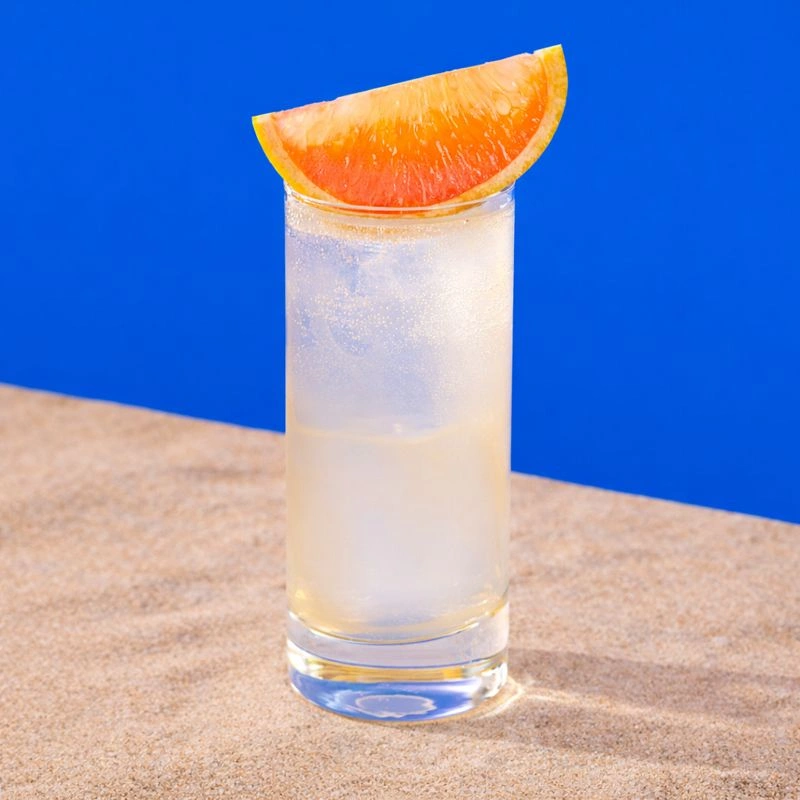 Cocktail à base de tequila, de sirop de lime, de sel et de soda au pamplemousse sur fond bleu royal.