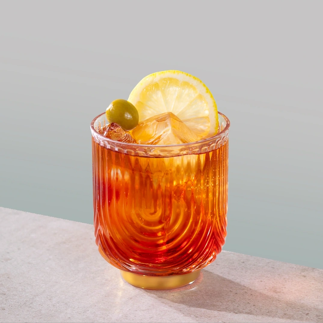 Cocktail made with Italian bitters, red vermouth and sparkling water on a grey background.