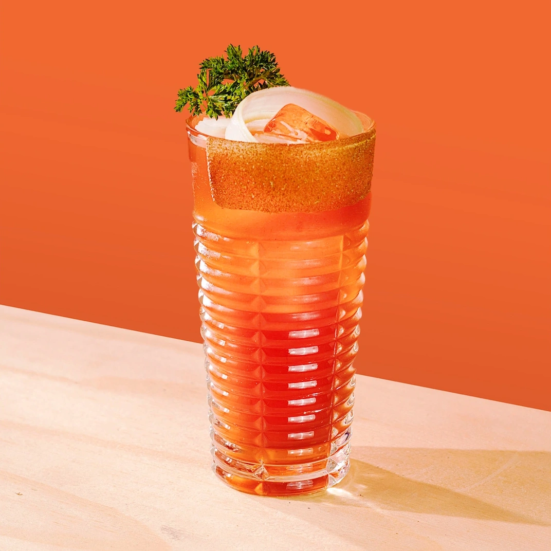 Cocktail à base de vodka, de mix à bloody et de clamato sur fond rouge.