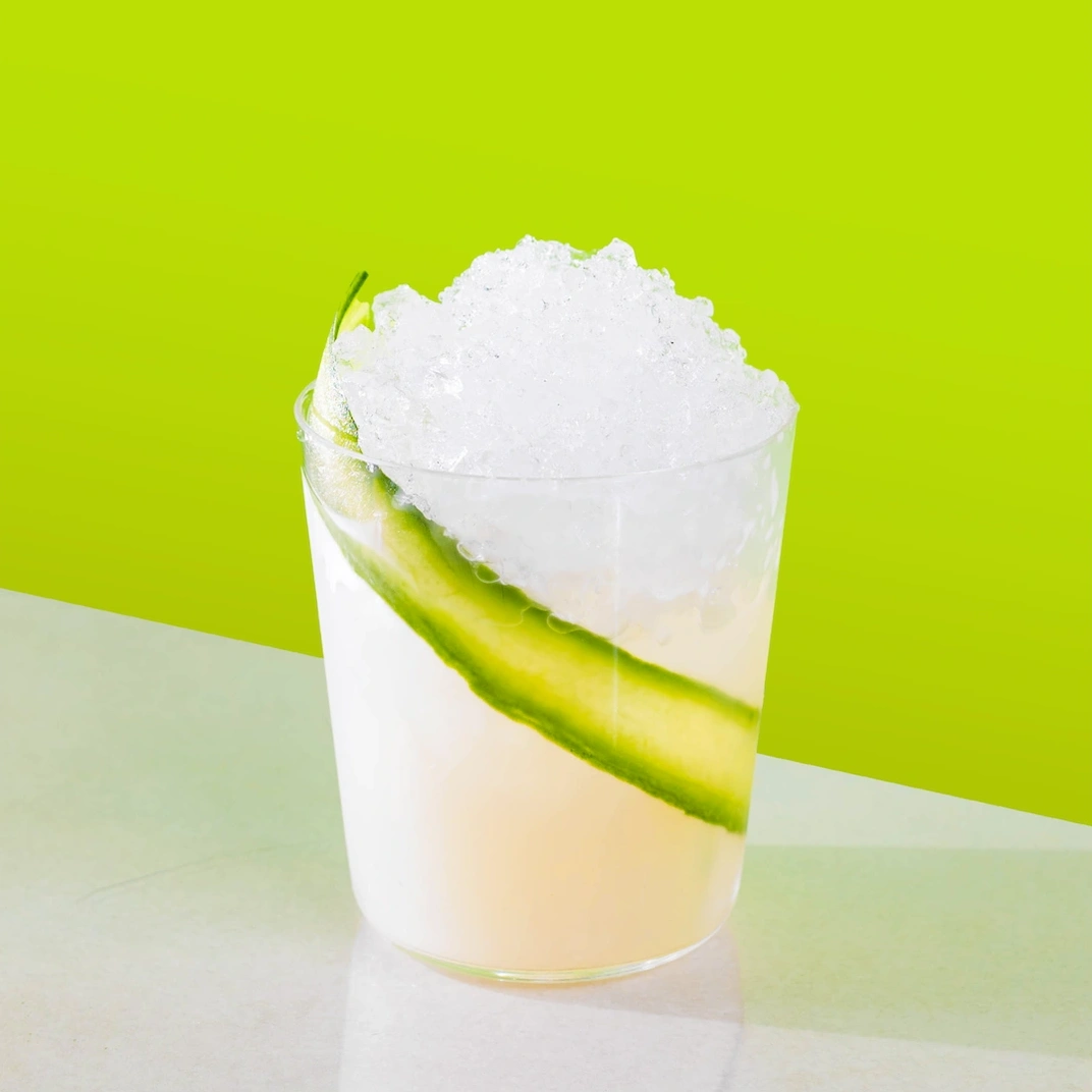 Cocktail made with absinthe, lime syrup and cold water on a green background.