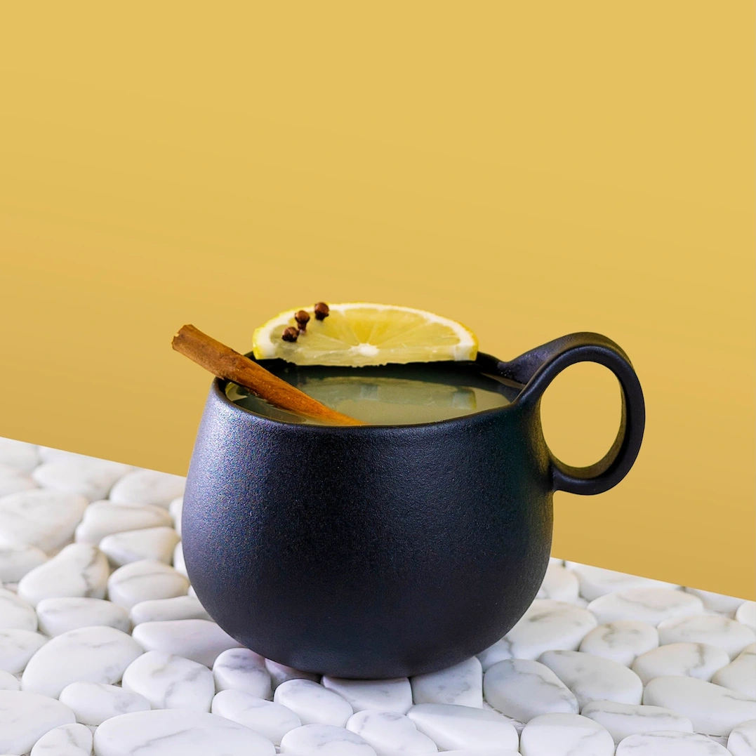 Toddy made with gin, hot toddy mix and hot water on a yellow background.
